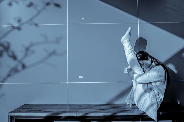 Woman performing a focused yoga movement in a minimalist space.
